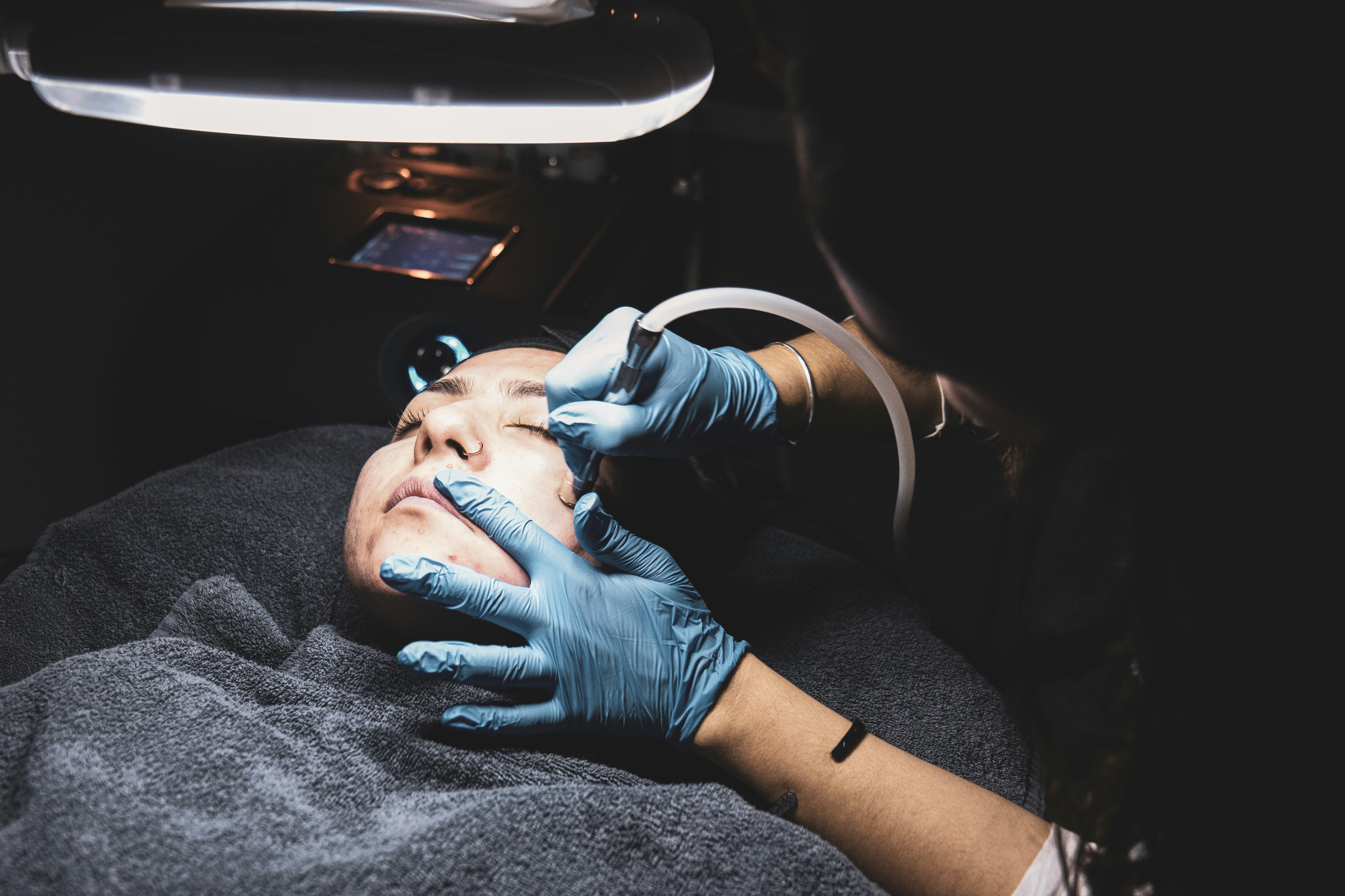 A provider examining a client’s skin under a magnifying lamp