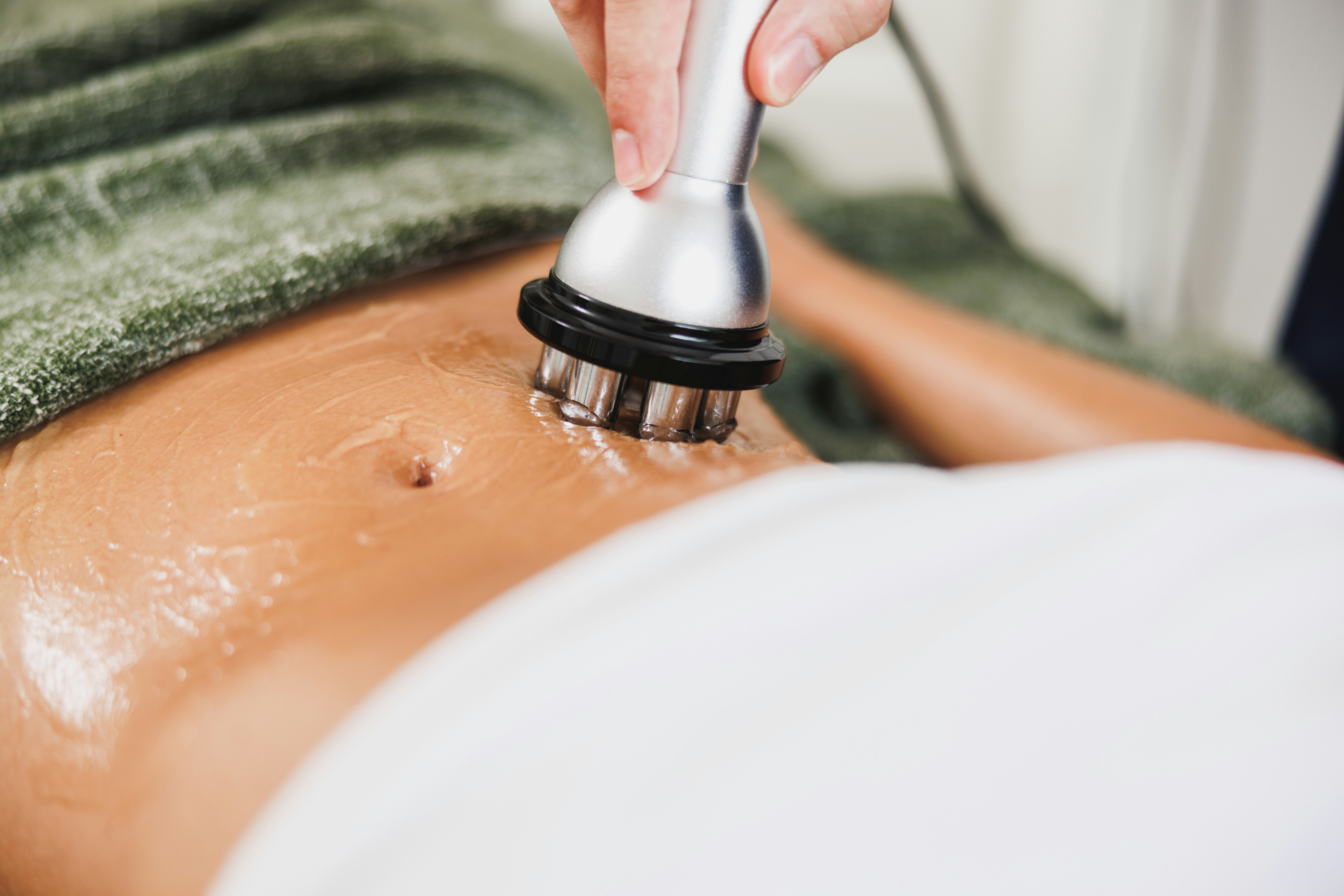 A body contouring applicator moving across a client’s abdomen