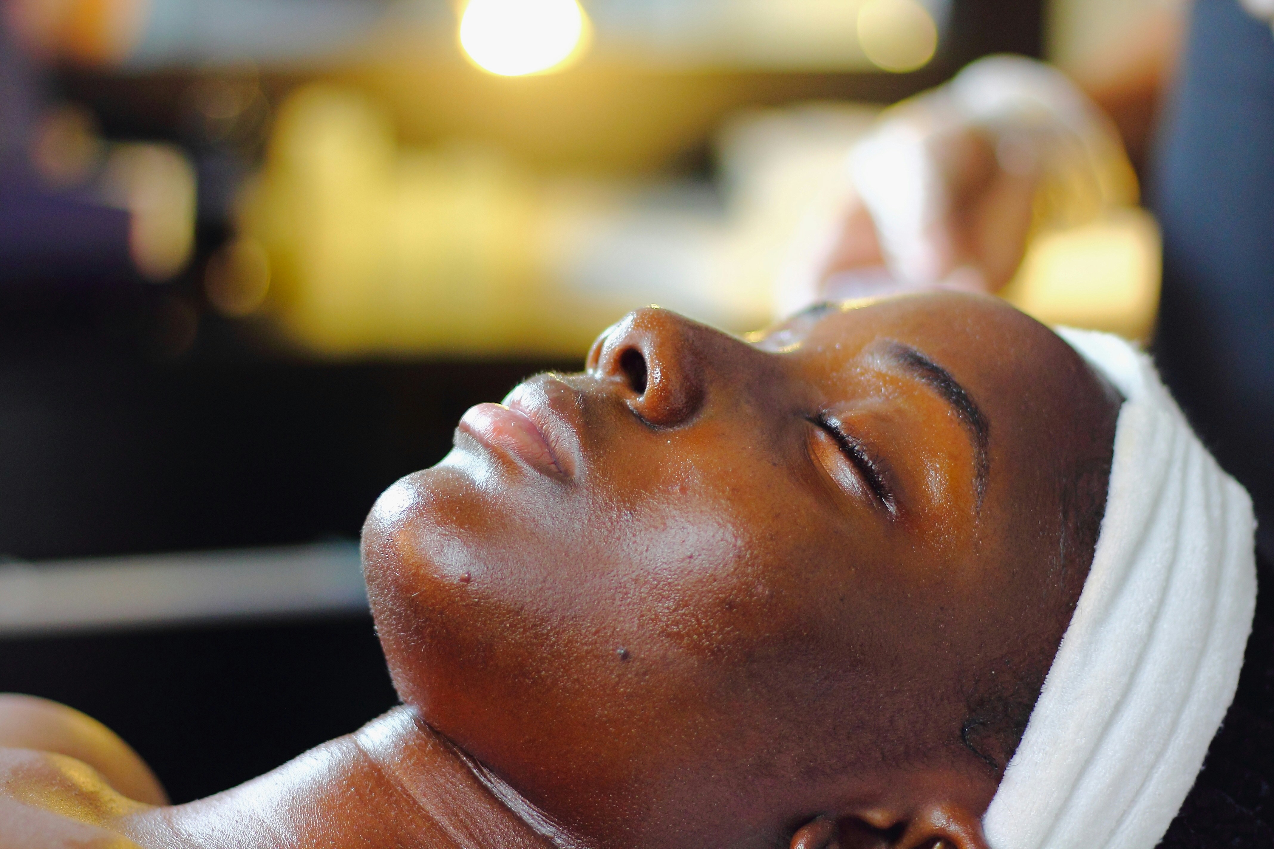 A client resting with her eyes closed and a headband on during a facial