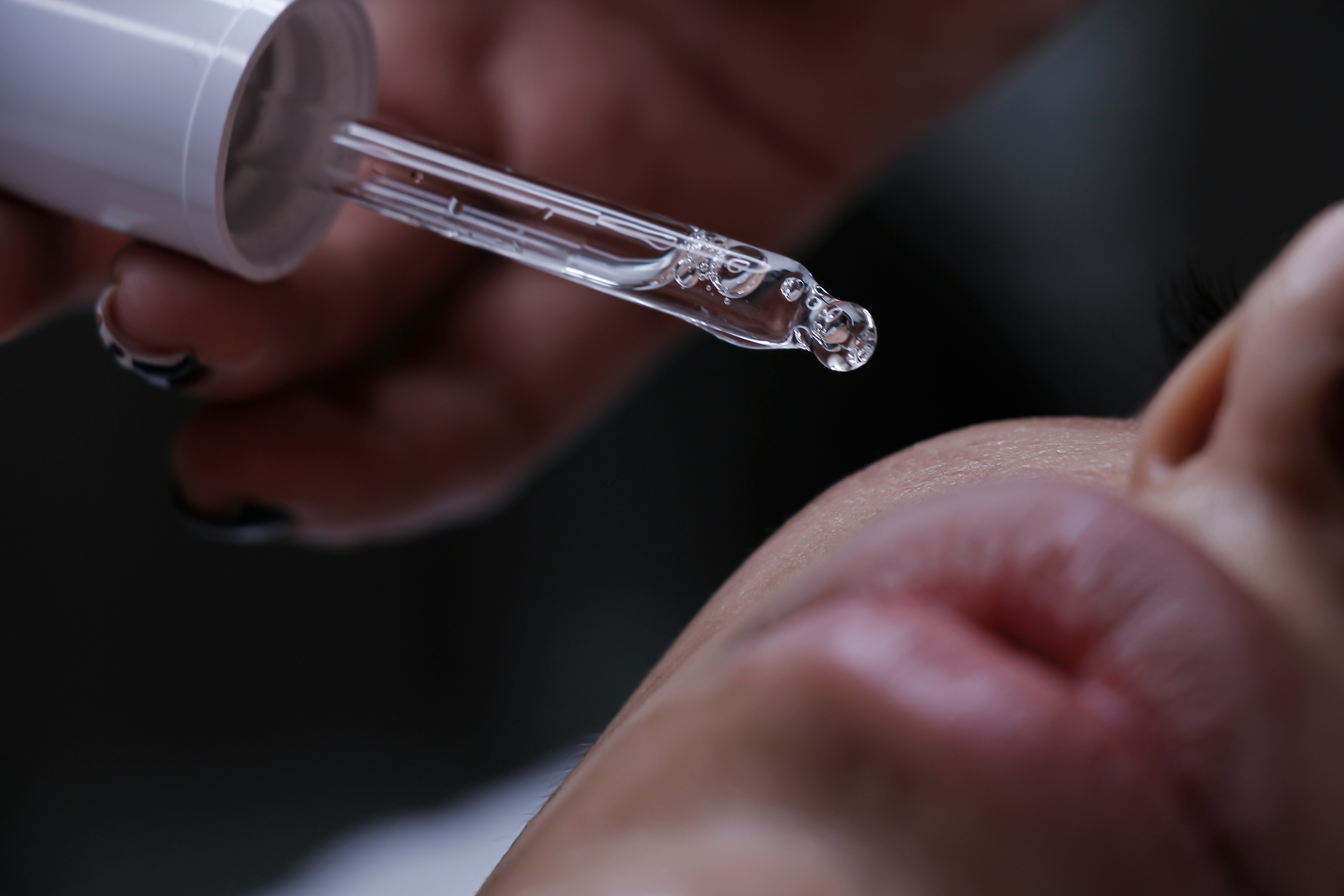 A dropper applying serum to a client’s skin after treatment